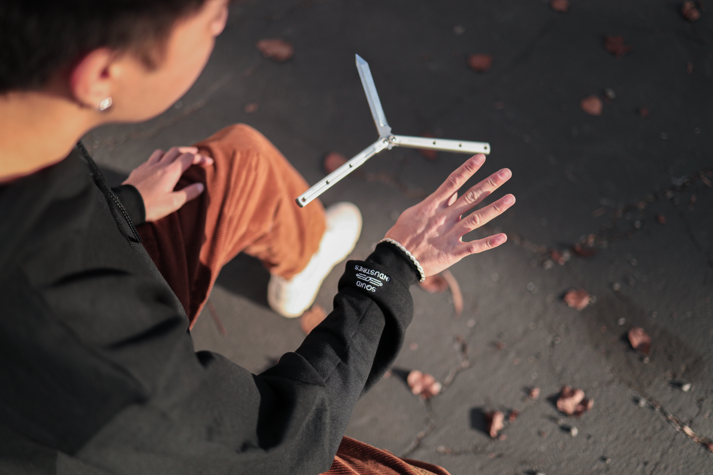 Picture of a man flipping a balisong knife. while wearing a Black Squiddy Squad Embroidered Champion Brand Hoodie