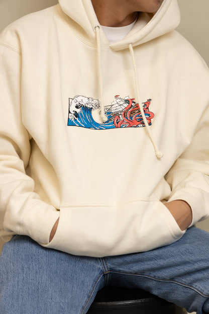 A close up view of a man wearing cream Squid Industries x Simple Stock Hoodie posing 