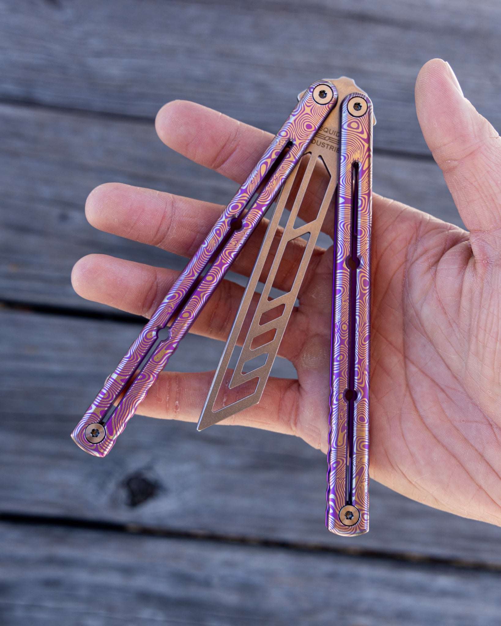 hand hold a magenta engraved damascus titanium krake raken 