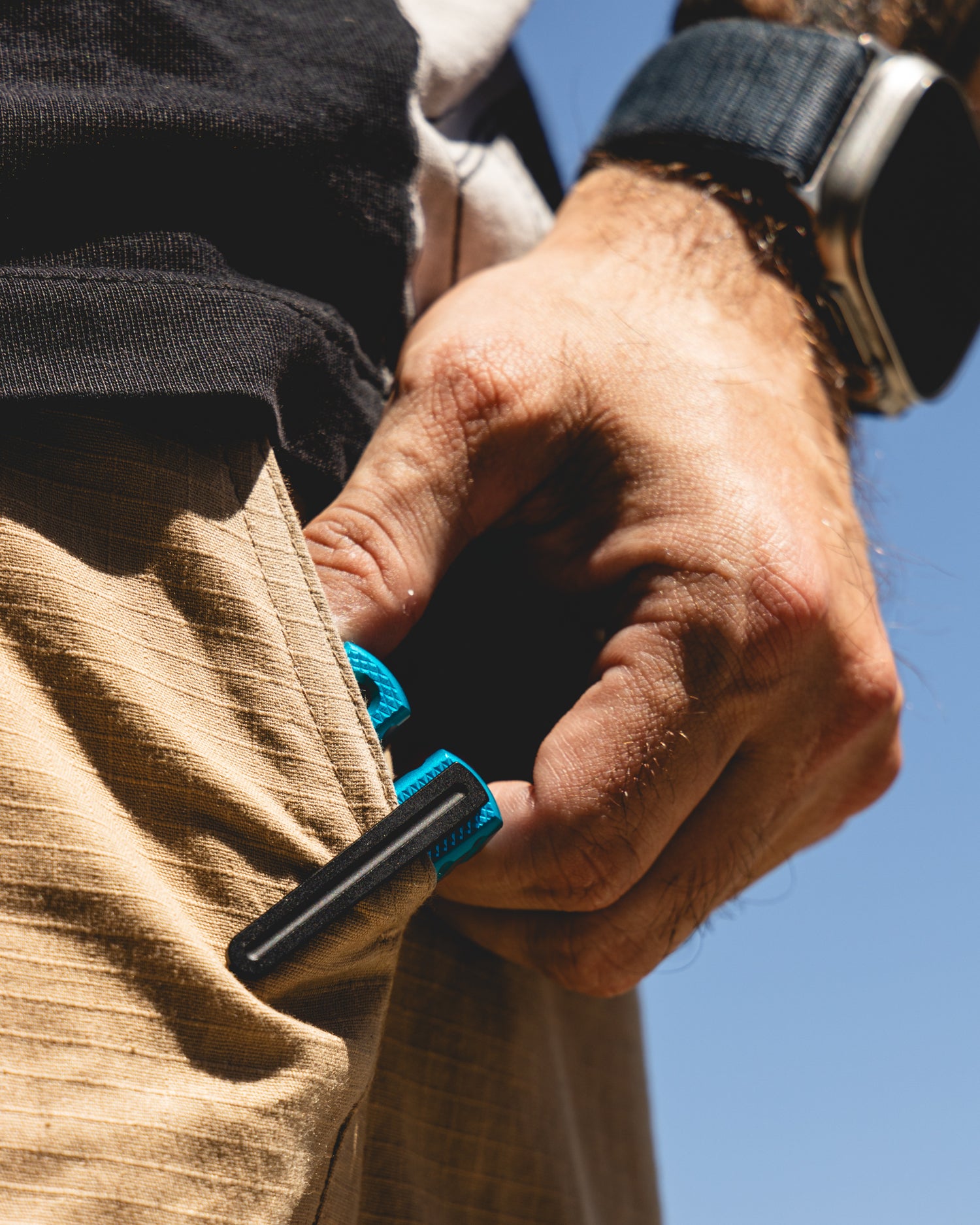 a man taking out a teal krake raken with black pocket clip attached