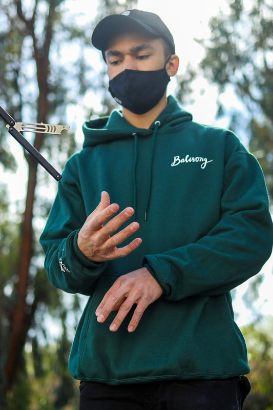 Man flipping a Mako Bottle Opener Squid Industries trainer while wearing a  Green balisong hoodie from squid indsutries 